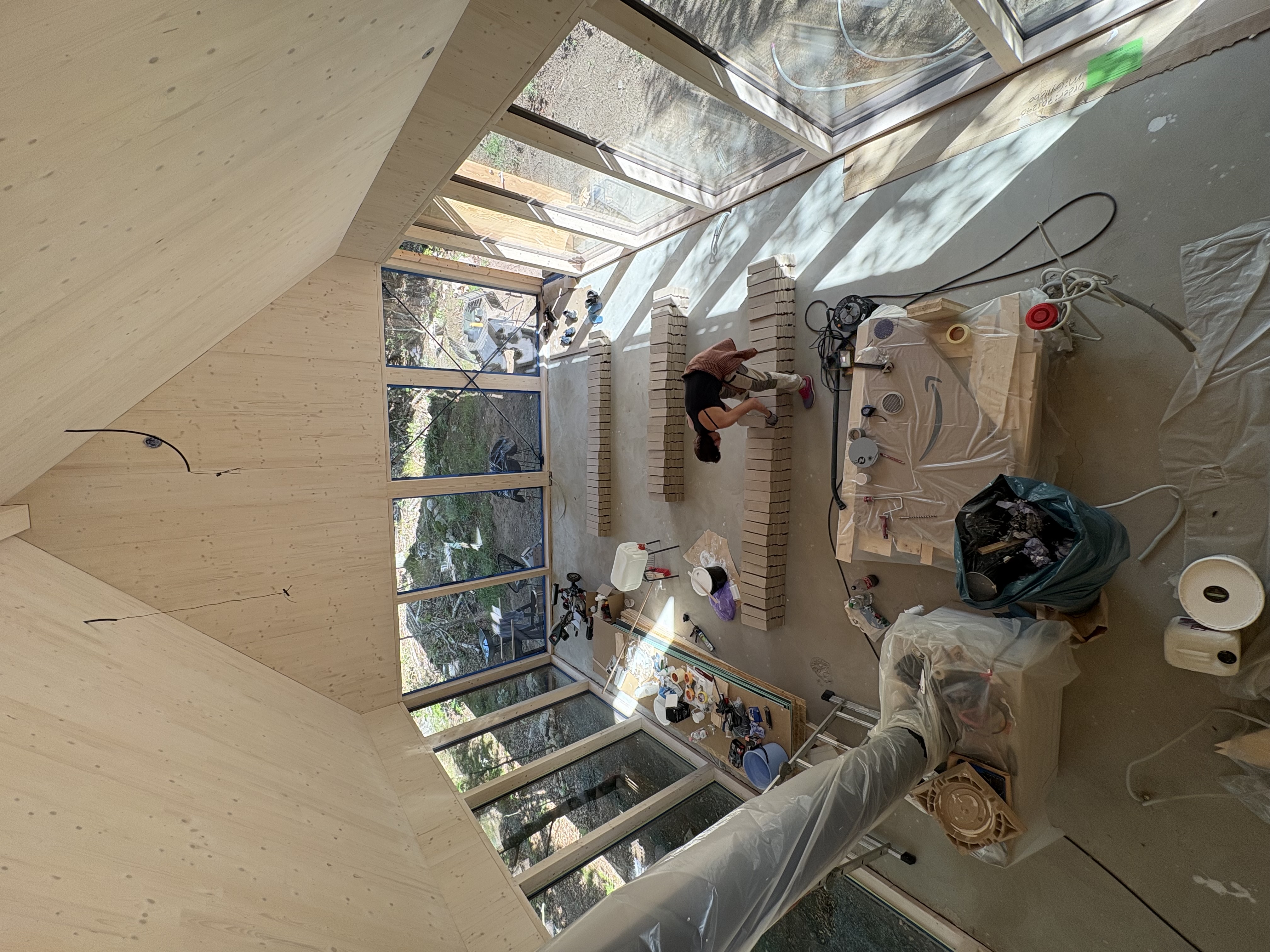Beech House under byggtiden sett från loftet ner mot tegelgolvet och glaspartierna