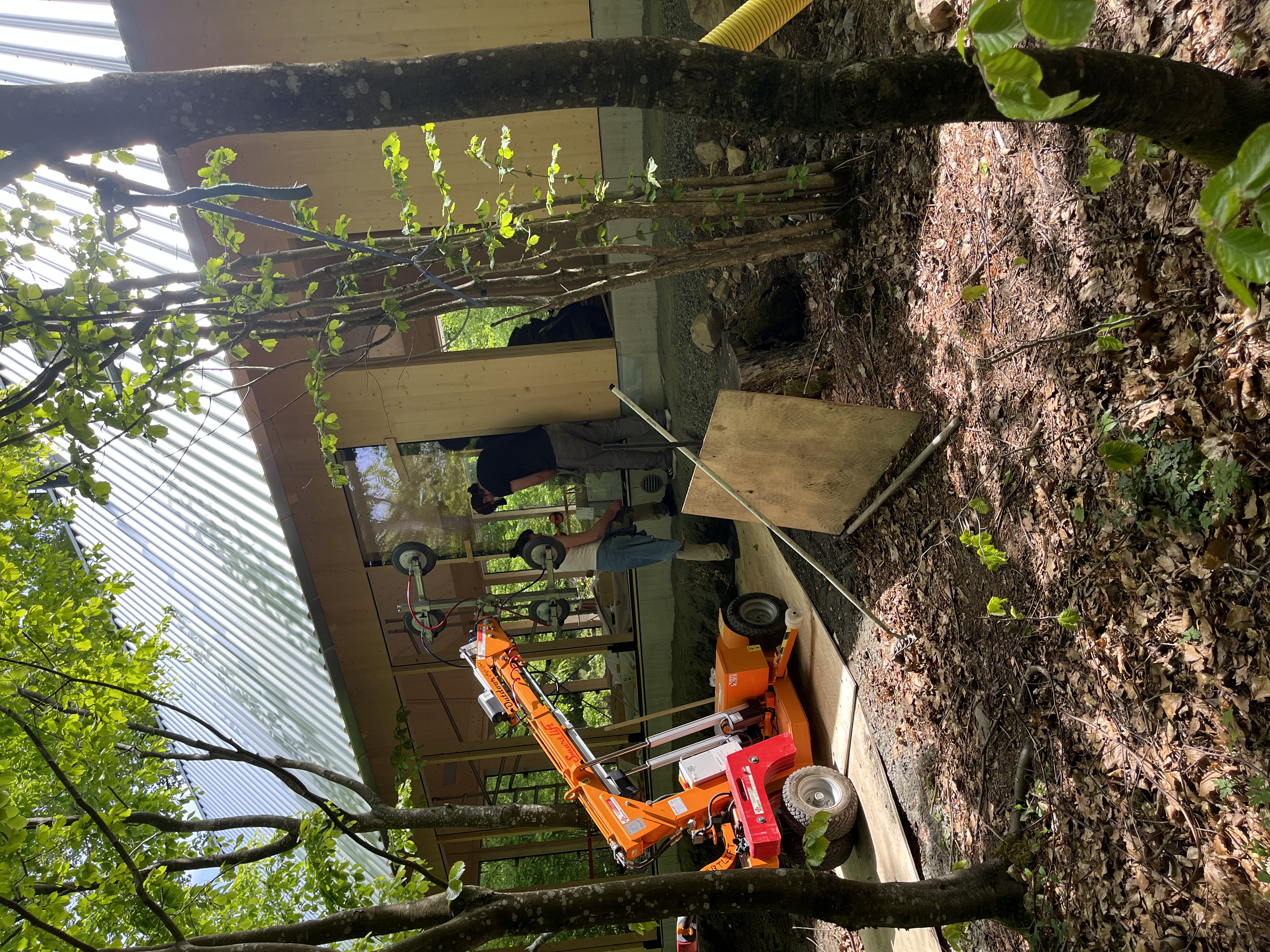Montering av ett stort isolerglas i Beech House med en orange glasrobot